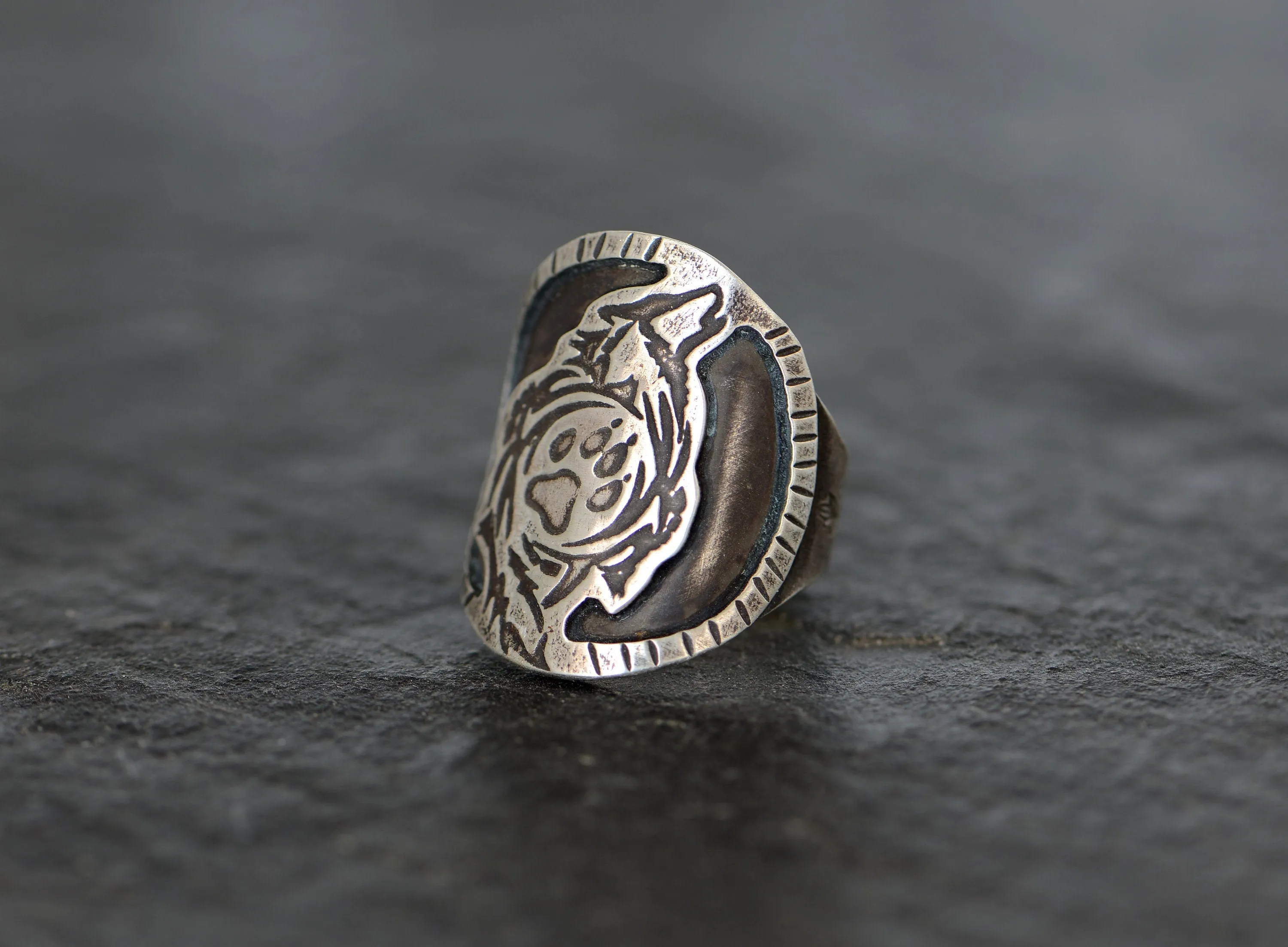 Saddle ring with howling wolf and paw design  in sterling silver